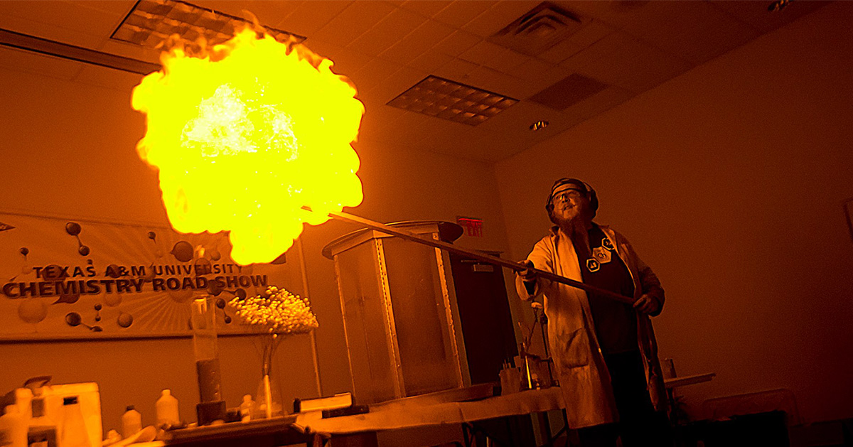 Chemistry Roadshow demonstration scientist displays a large glowing fireball presentation.