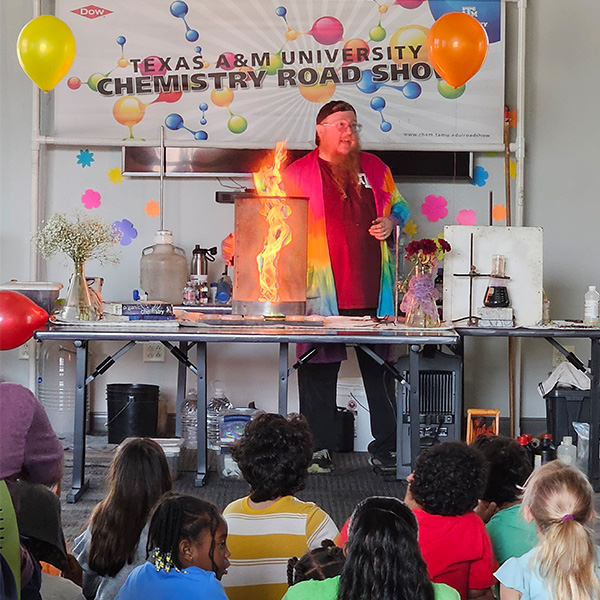 Chemistry Roadshow host presenting a science demonstration to a group of children. 