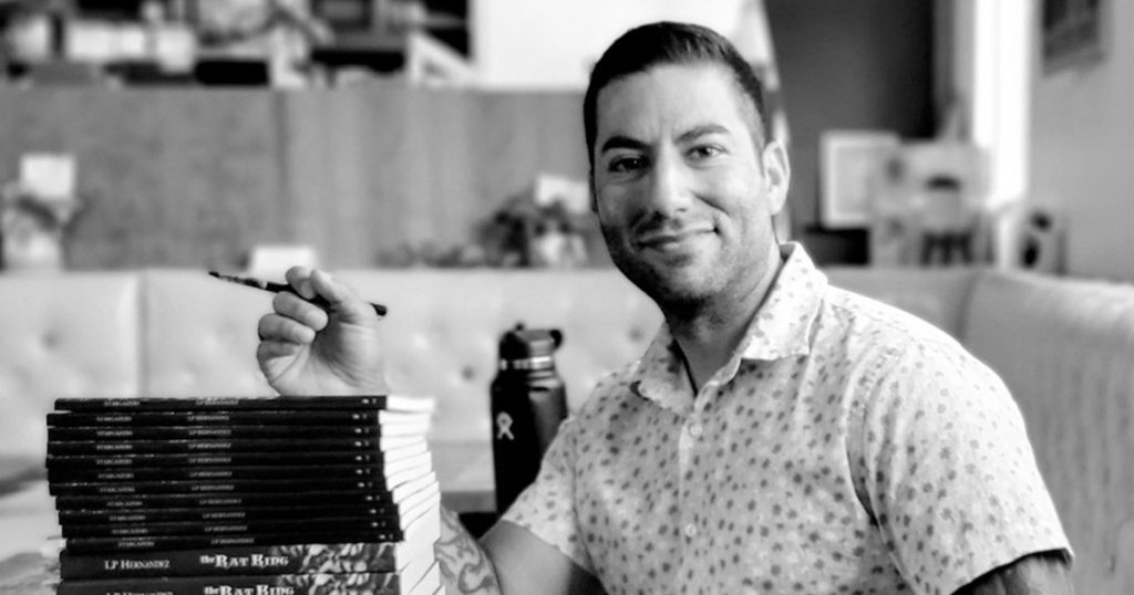 LP Hernandez sitting next to a stack of his books