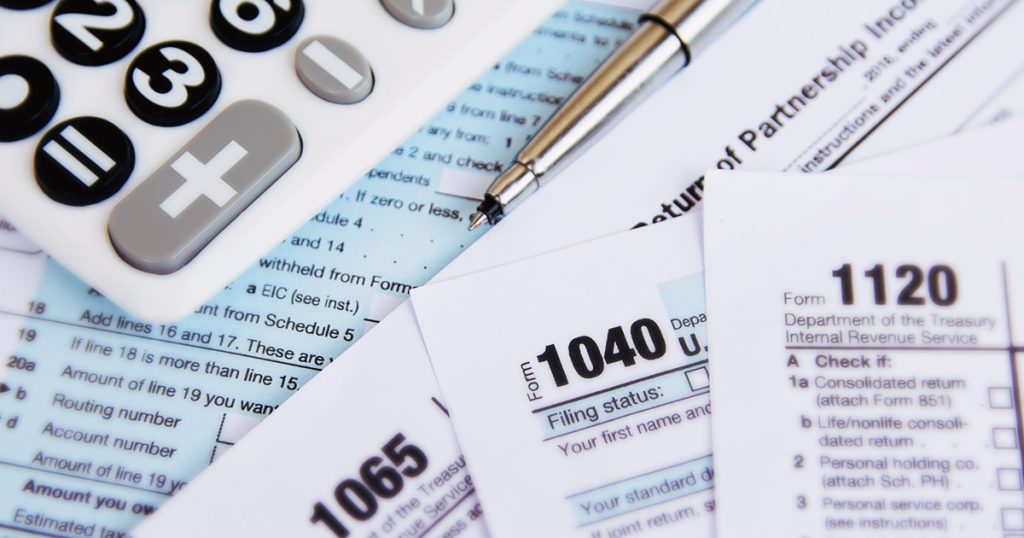 pile of tax paper documents with a calculator and pen